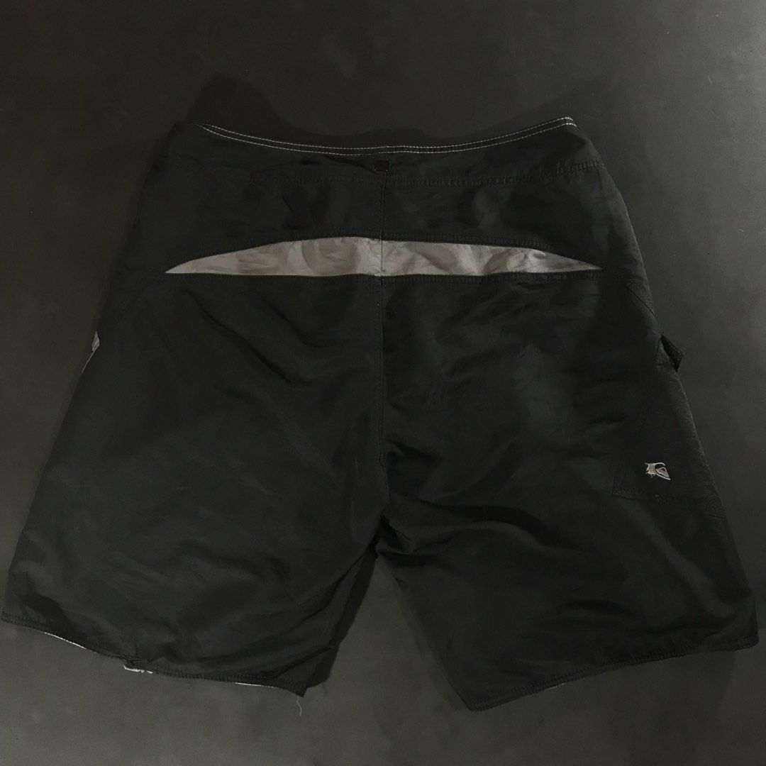 Quiksilver Board Shorts (Category: Swim Trunks & Board Shorts) located in Manila. Submitted by a_aron.f6e3a7 (Listing ID 1468787807, Image 3). Description: Size: W19 L22 • Color rate: 9/10 (Black with White Quiksilver Logo and White Hem Details) • Condition: Good pre-owned condition • Issues: Visible wrinkles and creases; slight fraying or wear may be present along the bottom hem.