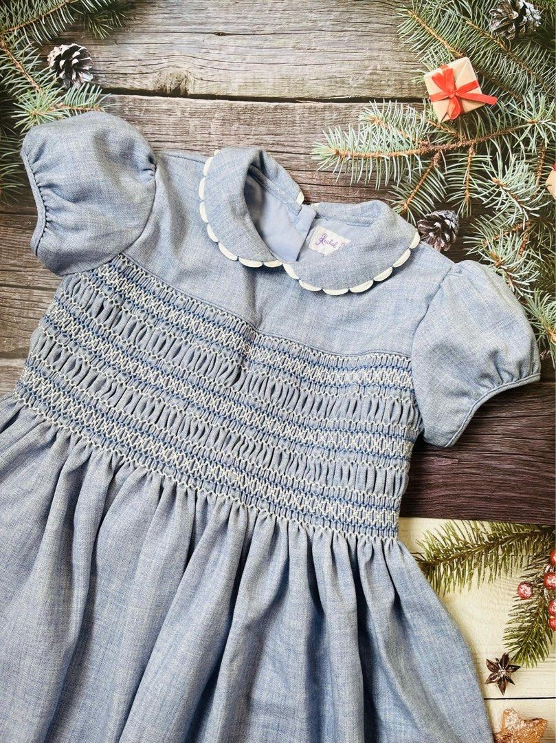 Rachel Riley Blue Smocked Dress with Collar (Category: Babies & Kids Fashion) located in Antipolo. Submitted by mlingc19 (Listing ID 1468856423, Image 2). Description: - Color: Light blue - Design: Hand-smocked chest, white scalloped Peter Pan collar - Sleeves: Short puff sleeves with gathered cuffs - Skirt: Flared with soft pleats - Closure: Back button closure with authentic brand label - Condition: Excellent, well-maintained - Shipping: Fast s