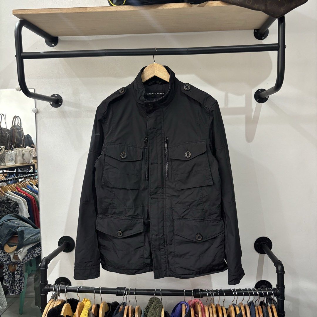 Ralph Lauren Black Utility Jacket with Multiple Pockets (Category: Coats, Jackets and Outerwear) located in Bambang. Submitted by heats777 (Listing ID 1468827917, Image 2). Description: - Brand: Ralph Lauren - Color: Black - Material: Durable nylon - Closure: Full zip front with snap button storm flap - Collar: Stand collar with shoulder epaulets - Pockets: Four front flap pockets and two vertical zippered chest pockets - Details: Branded hardwar