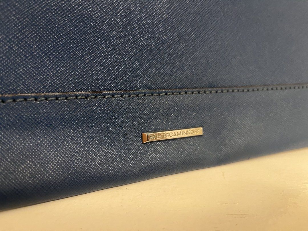 Rebecca Minkoff Blue Envelope Clutch Bag (Category: Luxury Bags & Wallets) located in Manila. Submitted by bellejnc (Listing ID 1468812870, Image 2). Description: - Brand: Rebecca Minkoff - Style: Envelope clutch - Material: Premium dark blue Saffiano leather - Hardware: Silver-tone zipper trim and metal back logo plate - Closure: Front envelope flap - Condition: Clean structure inside and out, minor scuff near zipper edge (see close-up photo) - 
