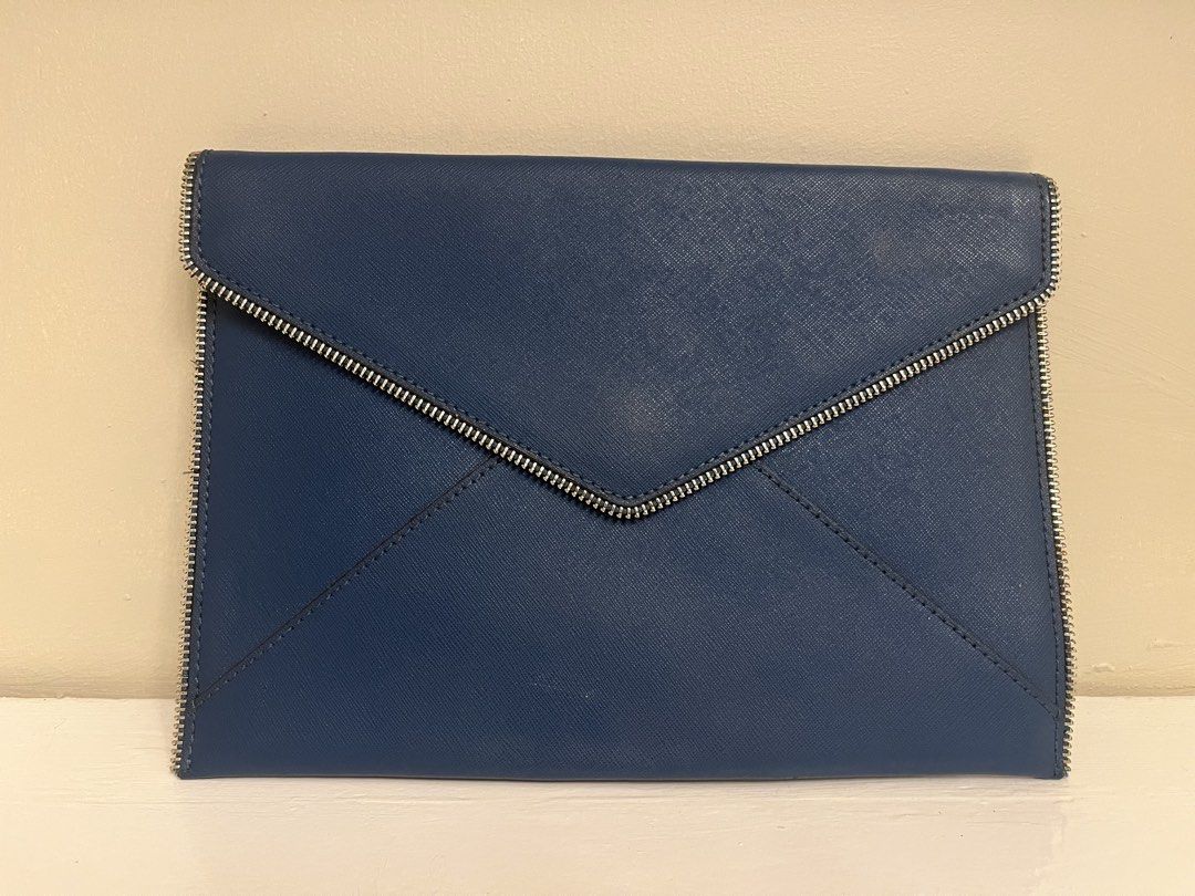 Rebecca Minkoff Blue Envelope Clutch Bag (Category: Luxury Bags & Wallets) located in Manila. Submitted by bellejnc (Listing ID 1468812870, Image 1). Description: - Brand: Rebecca Minkoff - Style: Envelope clutch - Material: Premium dark blue Saffiano leather - Hardware: Silver-tone zipper trim and metal back logo plate - Closure: Front envelope flap - Condition: Clean structure inside and out, minor scuff near zipper edge (see close-up photo) - 
