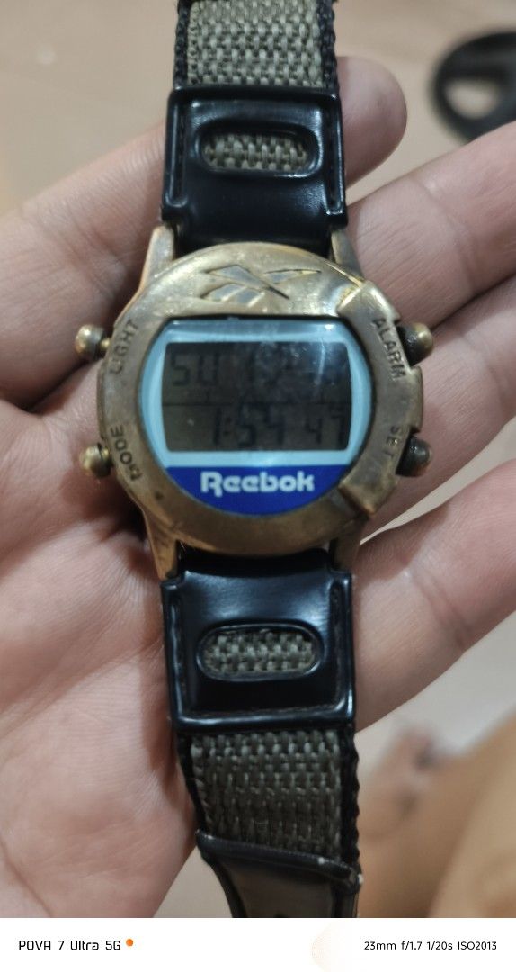 Reebok Vintage Watch PH movement (Category: Men's Watches) located in Quezon City. Submitted by junseller18 (Listing ID 1468758579, Image 3). Description: Rare time piece, newly replaced battery (Toshiba CR2016 Oct 18, 2026) . -Scatches on the glass. (see actual photos) - Brand: Reebok (Vintage model with Philippines movement) - Display: Digital screen showing time, day, and date - Design: Brass-tone bezel with iconic Reebok logo at the top - Str