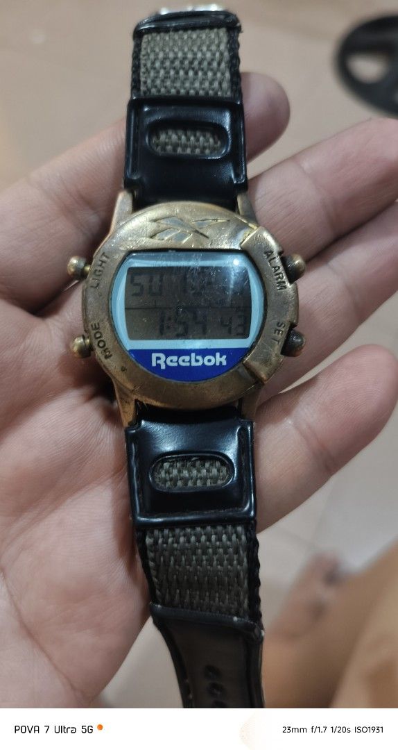 Reebok Vintage Watch PH movement (Category: Men's Watches) located in Quezon City. Submitted by junseller18 (Listing ID 1468758579, Image 1). Description: Rare time piece, newly replaced battery (Toshiba CR2016 Oct 18, 2026) . -Scatches on the glass. (see actual photos) - Brand: Reebok (Vintage model with Philippines movement) - Display: Digital screen showing time, day, and date - Design: Brass-tone bezel with iconic Reebok logo at the top - Str