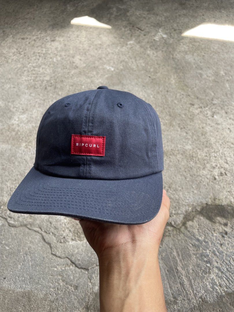 Ripcurl Navy Snapback Cap With Red Box Logo (Category: Caps & Hats) located in General Santos City (Dadiangas). Submitted by christbluee (Listing ID 1468826238, Image 2). Description: - Color: Dark navy blue - Brand: Ripcurl (The Classics Yupoong interior tag) - Design: Red rectangular patch logo with white lettering on the front - Fit: Structured crown, curved brim, and adjustable plastic snapback closure - Condition: Excellent, stylish everyday