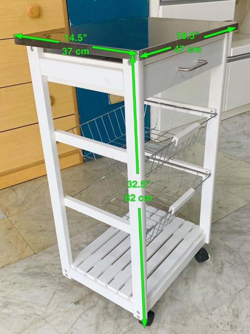 Rolling kitchen utility (Category: Bathroom & Kitchen Fixtures) located in Quezon City. Submitted by cmagday (Listing ID 1468802456, Image 3). Description: white rolling kitchen utility and serving trolley featuring a stainless steel top, a pull-out storage drawer, two wire metal vegetable baskets, a slatted bottom shelf, and caster wheels. material: White Wood & metal.