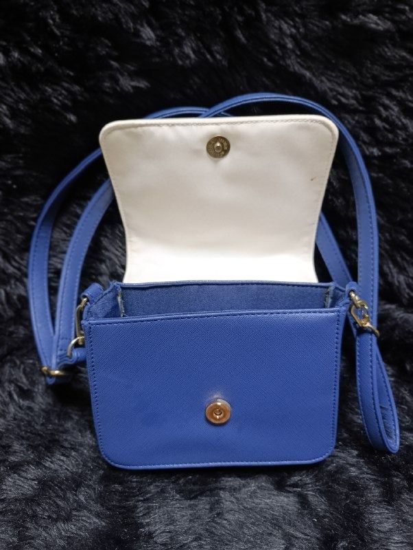 Sanrio Hello Kitty Blue Crossbody Bag (Category: Cross-body Bags) located in Iloilo. Submitted by jpk_ok_sales (Listing ID 1468797203, Image 3). Description: - Authentic Sanrio Kitty merchandise with official tag inside - Chic blue and white colorway in a trendy structured square shape - Adorable embroidered Kitty face detail on the front flap - Secure magnetic snap closure - Versatile design featuring a top handle and an adjustable/removable sho