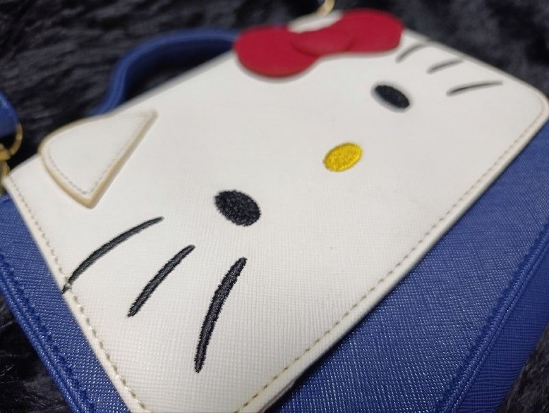 Sanrio Hello Kitty Blue Crossbody Bag (Category: Cross-body Bags) located in Iloilo. Submitted by jpk_ok_sales (Listing ID 1468797203, Image 2). Description: - Authentic Sanrio Kitty merchandise with official tag inside - Chic blue and white colorway in a trendy structured square shape - Adorable embroidered Kitty face detail on the front flap - Secure magnetic snap closure - Versatile design featuring a top handle and an adjustable/removable sho