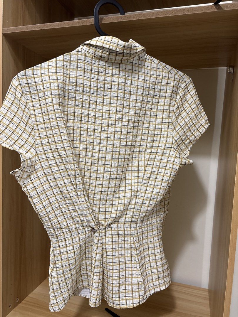 Short sleeve plaid collared button up blouse (Category: Blouses) located in Manila. Submitted by krinpet (Listing ID 1468858573, Image 2). Description: - Color/Pattern: Yellow and dark grey plaid on white background - Material: Lightweight and textured seersucker fabric - Design: Short sleeves, classic lapel collar, and button-down front - Special Detail: Stylish knotted back for a cinched waist silhouette - Fit: True to size, great for casual ev