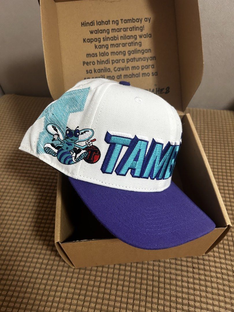 SIGNED Tambay Pilipinas Snapback Hat with Box (Category: Caps & Hats) located in Antipolo. Submitted by cl026 (Listing ID 1468723264, Image 2). Description: - Brand: Tambay Pilipinas -Signed by Pio Balbuena - Style: Snapback hat in a white, purple, and blue colorway - Details: Embroidered front logo and side mascot graphic with a classic green underbrim - Fit: Adjustable snap closure at the back for a customized fit - Condition: Brand new and unw
