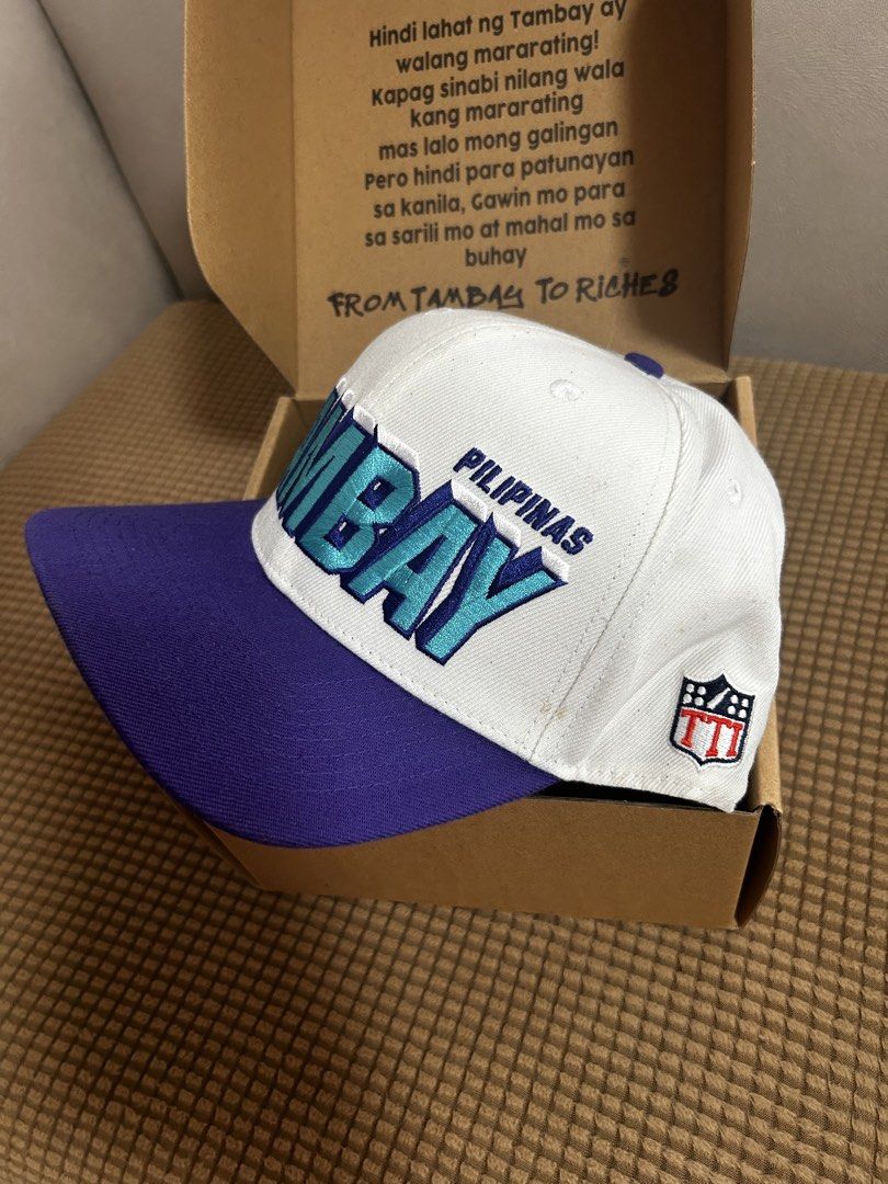 SIGNED Tambay Pilipinas Snapback Hat with Box (Category: Caps & Hats) located in Antipolo. Submitted by cl026 (Listing ID 1468723264, Image 3). Description: - Brand: Tambay Pilipinas -Signed by Pio Balbuena - Style: Snapback hat in a white, purple, and blue colorway - Details: Embroidered front logo and side mascot graphic with a classic green underbrim - Fit: Adjustable snap closure at the back for a customized fit - Condition: Brand new and unw