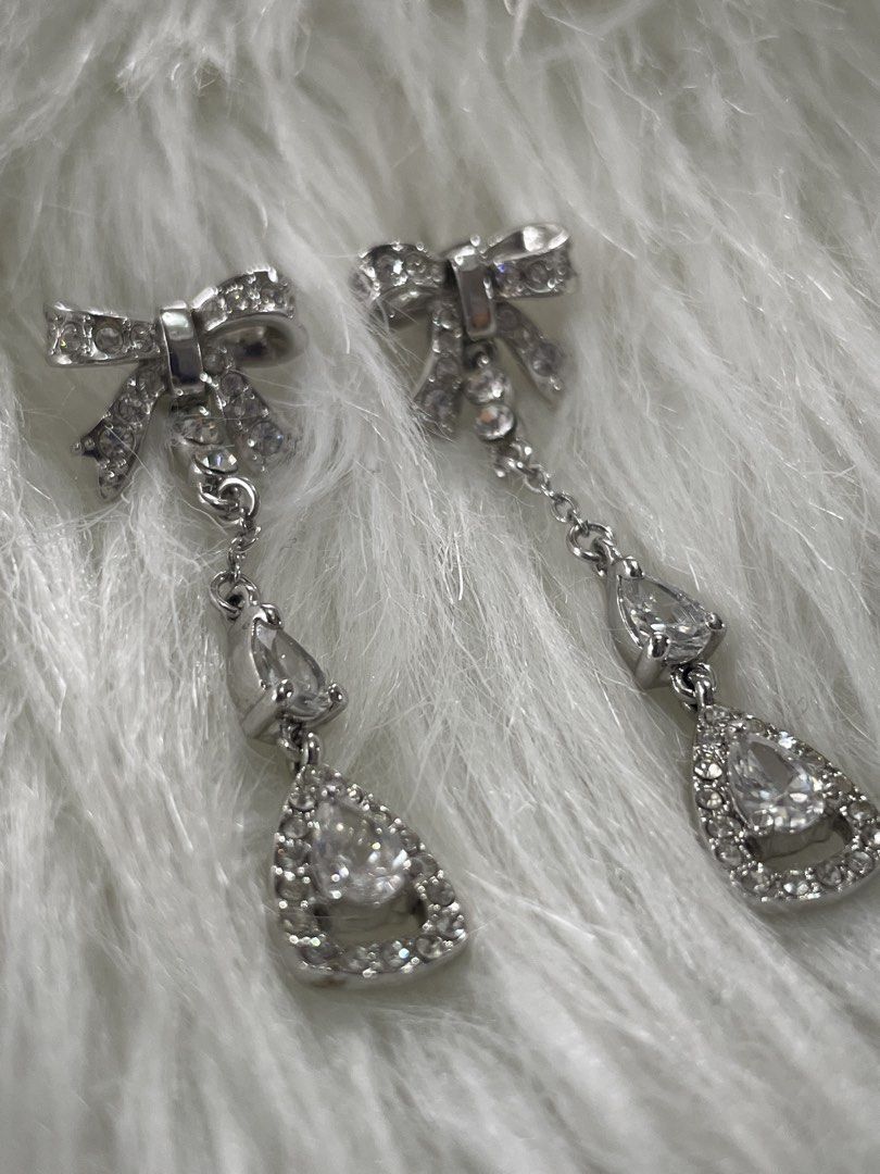 Silver Bow Rhinestone Drop Earrings (Category: Earrings) located in San Juan City. Submitted by redrosierose (Listing ID 1468716858, Image 3). Description: - Elegant silver dangle earrings with charming bow studs - Adorned with small rhinestone chains leading to a pear-shaped crystal drop - Catches the light beautifully for maximum sparkle - Secure post back closure - Ideal for weddings, parties, and dressed-up dinners RFS: Decluttering LOC: San 