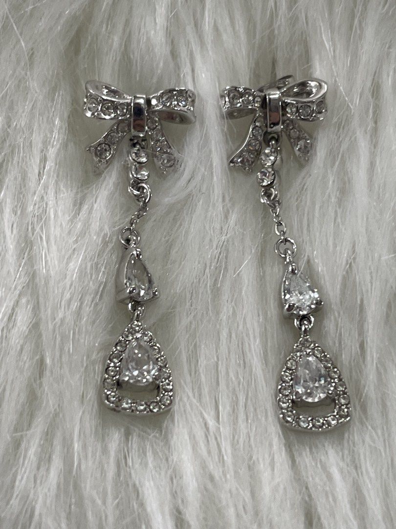 Silver Bow Rhinestone Drop Earrings (Category: Earrings) located in San Juan City. Submitted by redrosierose (Listing ID 1468716858, Image 1). Description: - Elegant silver dangle earrings with charming bow studs - Adorned with small rhinestone chains leading to a pear-shaped crystal drop - Catches the light beautifully for maximum sparkle - Secure post back closure - Ideal for weddings, parties, and dressed-up dinners RFS: Decluttering LOC: San 