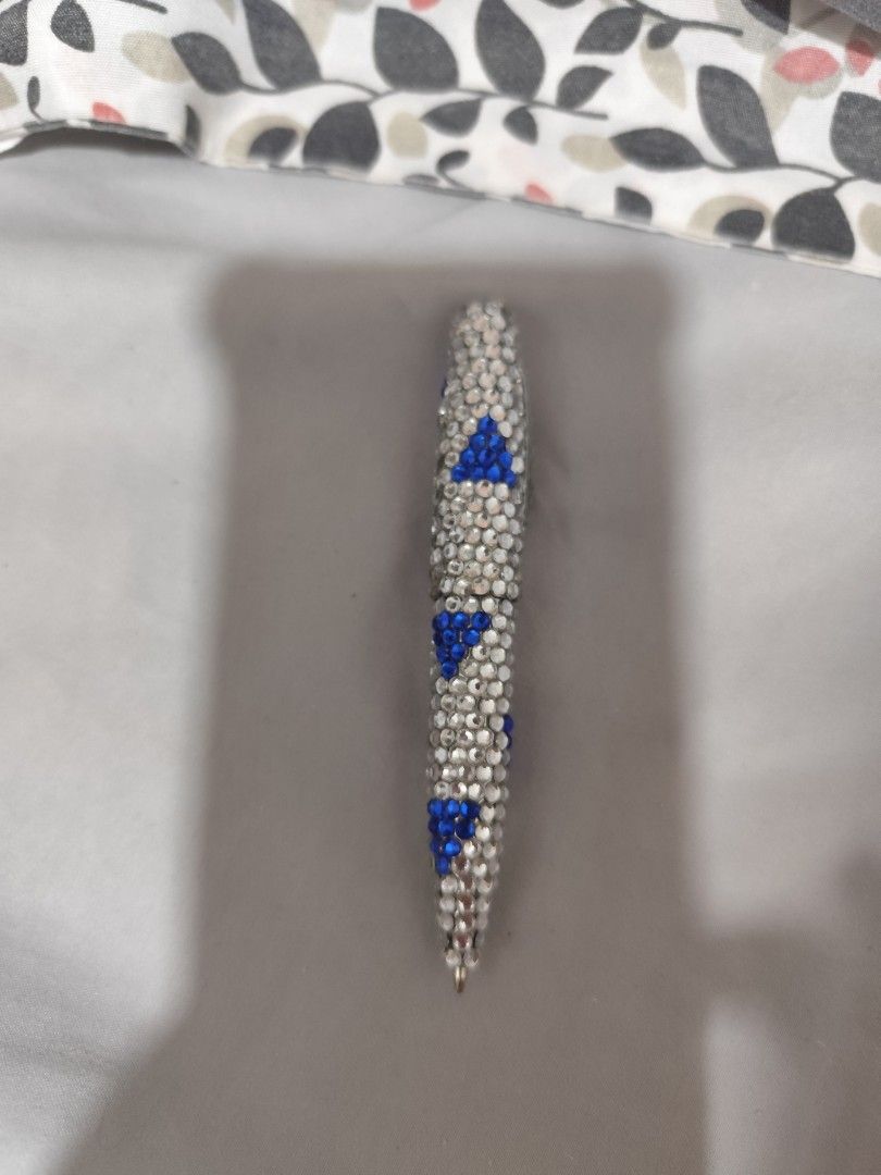 Sparkly Rhinestone Pen with Blue Accents (Category: Stationery & School Supplies) located in Manila. Submitted by marriage031073advocate (Listing ID 1468744307, Image 2). Description: - Stunning rhinestone-covered barrel with blue crystal triangular patterns - Equipped with a convenient pocket clip on the top cap - Writes smoothly for everyday use - Makes a fantastic desk accessory or gift idea.
