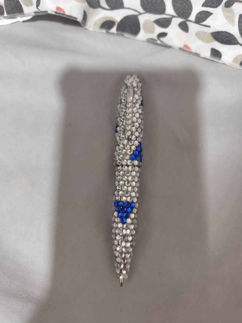 Sparkly Rhinestone Pen with Blue Accents (Category: Stationery & School Supplies) located in Manila. Submitted by marriage031073advocate (Listing ID 1468744307, Image 1). Description: - Stunning rhinestone-covered barrel with blue crystal triangular patterns - Equipped with a convenient pocket clip on the top cap - Writes smoothly for everyday use - Makes a fantastic desk accessory or gift idea.