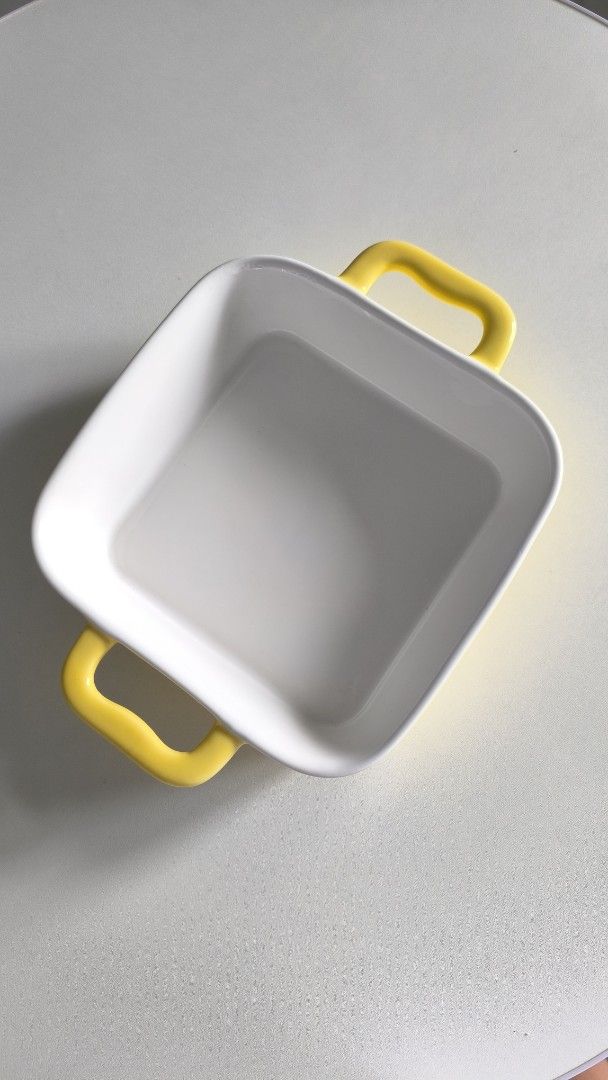 Square ceramic baking dish with yellow handles (Category: Bakeware) located in Manila. Submitted by tinebellen (Listing ID 1468743286, Image 2). Description: - Type: Square baking dish - Color: White with bright yellow handles - Material: Thick ceramic - Ideal for: Small casseroles or single servings - Condition: Used a couple of times, still in great shape (no chips or cracks) - Features: Handy side handles for safe and easy oven removal Japan S