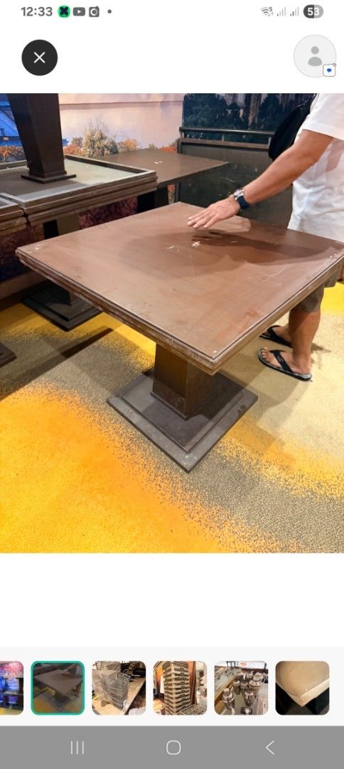 Square Wooden Table with Central Pedestal Base (Category: Tables & Sets) located in Las Pinas. Submitted by jesus1smysavi0r (Listing ID 1468738605, Image 2). Description: - Solid wooden square table in a rich brown finish - Thick top featuring a stylish paneled design - Heavy central pedestal base with a square tiered floor plate for stability - Standard dining/accent height - Sturdy and heavy construction - Note: Shows some scuffs and wear marks