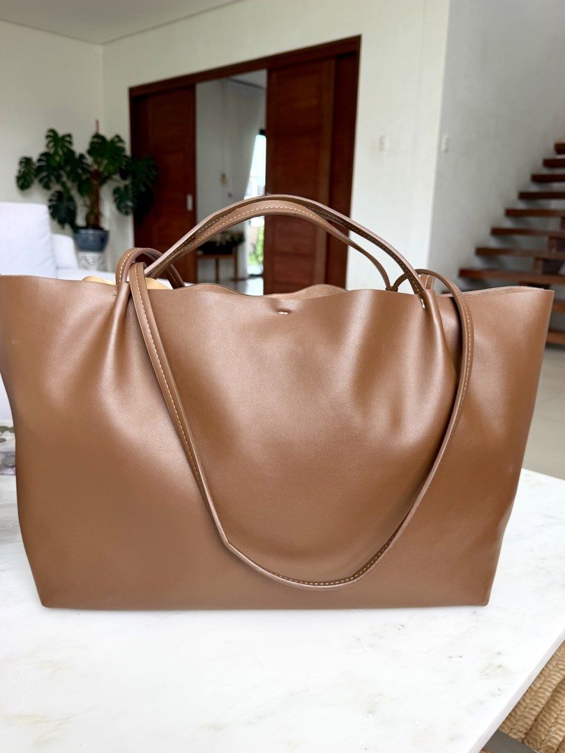 Zara Tan Tote Bag (Category: Tote Bags) located in Lipa City. Submitted by pauline0303 (Listing ID 1468715999, Image 3). Description: - Color: Classic brown - Material: Premium soft leather with soft interior lining - Design: Minimalist style with contrast white stitching on handles and base - Structure: Spacious open interior with a rectangular base to hold its shape - Versatility: Dual shoulder straps for shoulder and arm, perfect for daily wea