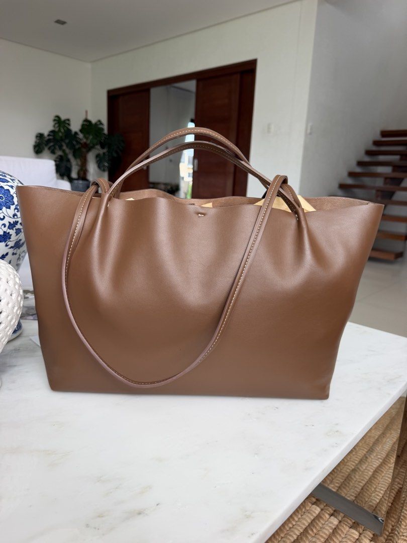 Zara Tan Tote Bag (Category: Tote Bags) located in Lipa City. Submitted by pauline0303 (Listing ID 1468715999, Image 2). Description: - Color: Classic brown - Material: Premium soft leather with soft interior lining - Design: Minimalist style with contrast white stitching on handles and base - Structure: Spacious open interior with a rectangular base to hold its shape - Versatility: Dual shoulder straps for shoulder and arm, perfect for daily wea