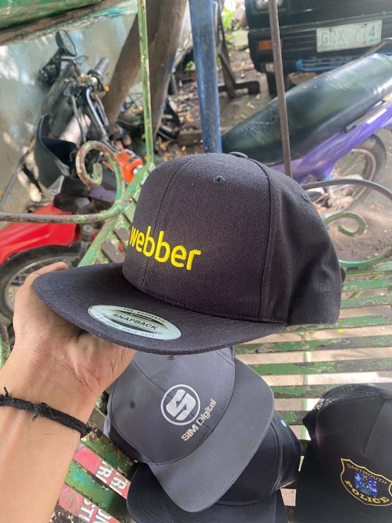 The Classics Yupoong Snapback Cap Webber Yellow Text Black (Category: Caps & Hats) located in Sibulan. Submitted by thethiftedcap0728 (Listing ID 1468734951, Image 3). Description: - Brand: The Classics Yupoong - Style: Classic flat brim snapback cap with green underbrim - Design: Eye-catching bright yellow "webber" embroidery on the front - Material: 80% acrylic, 20% wool blend (Made in Bangladesh) - Closure: Adjustable plastic snapback for a cu