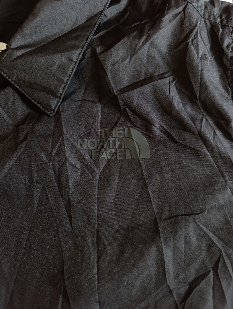 The North Face Black Coach Jacket Windbreaker (Category: Coats, Jackets and Outerwear) located in Cebu City. Submitted by jomeljakeg85353 (Listing ID 1468765216, Image 3). Description: - Brand: The North Face - Color: Solid black - Material: Lightweight nylon - Closure: Classic fold-down collar with front snap-button closure - Pockets: Two front hand pockets - Details: Elastic cuffs, straight hem, and subtle tonal logo on upper left chest - Style