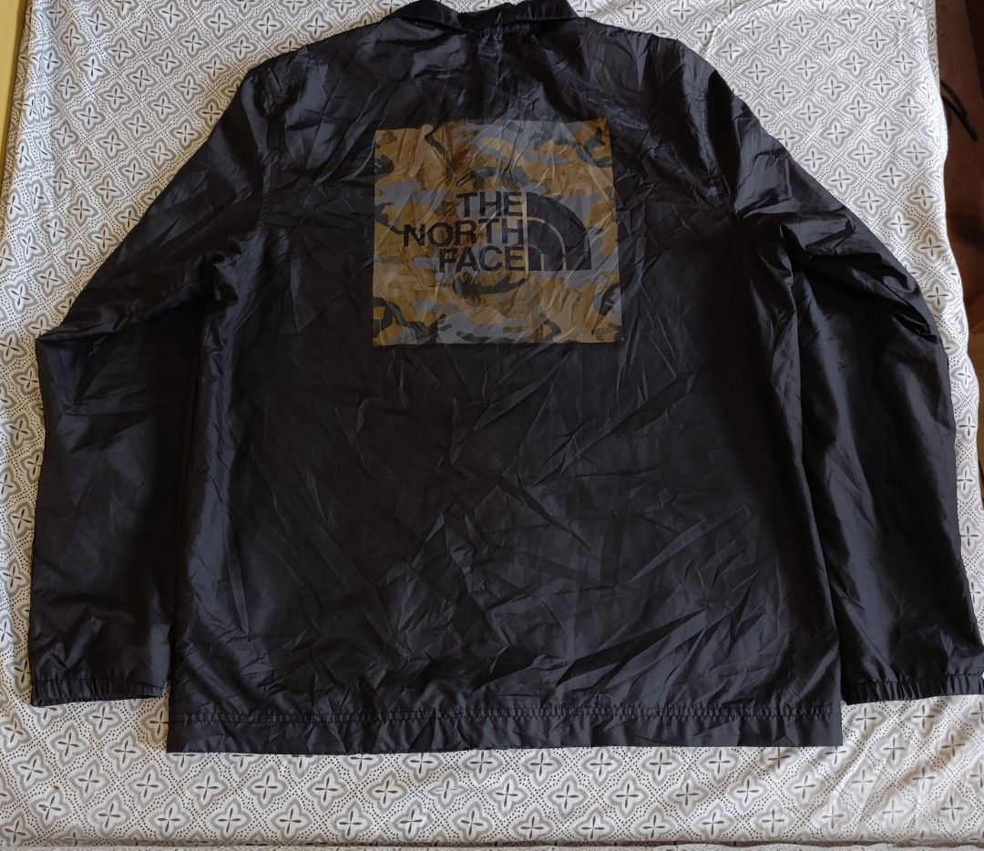 The North Face Black Coach Jacket Windbreaker (Category: Coats, Jackets and Outerwear) located in Cebu City. Submitted by jomeljakeg85353 (Listing ID 1468765216, Image 2). Description: - Brand: The North Face - Color: Solid black - Material: Lightweight nylon - Closure: Classic fold-down collar with front snap-button closure - Pockets: Two front hand pockets - Details: Elastic cuffs, straight hem, and subtle tonal logo on upper left chest - Style