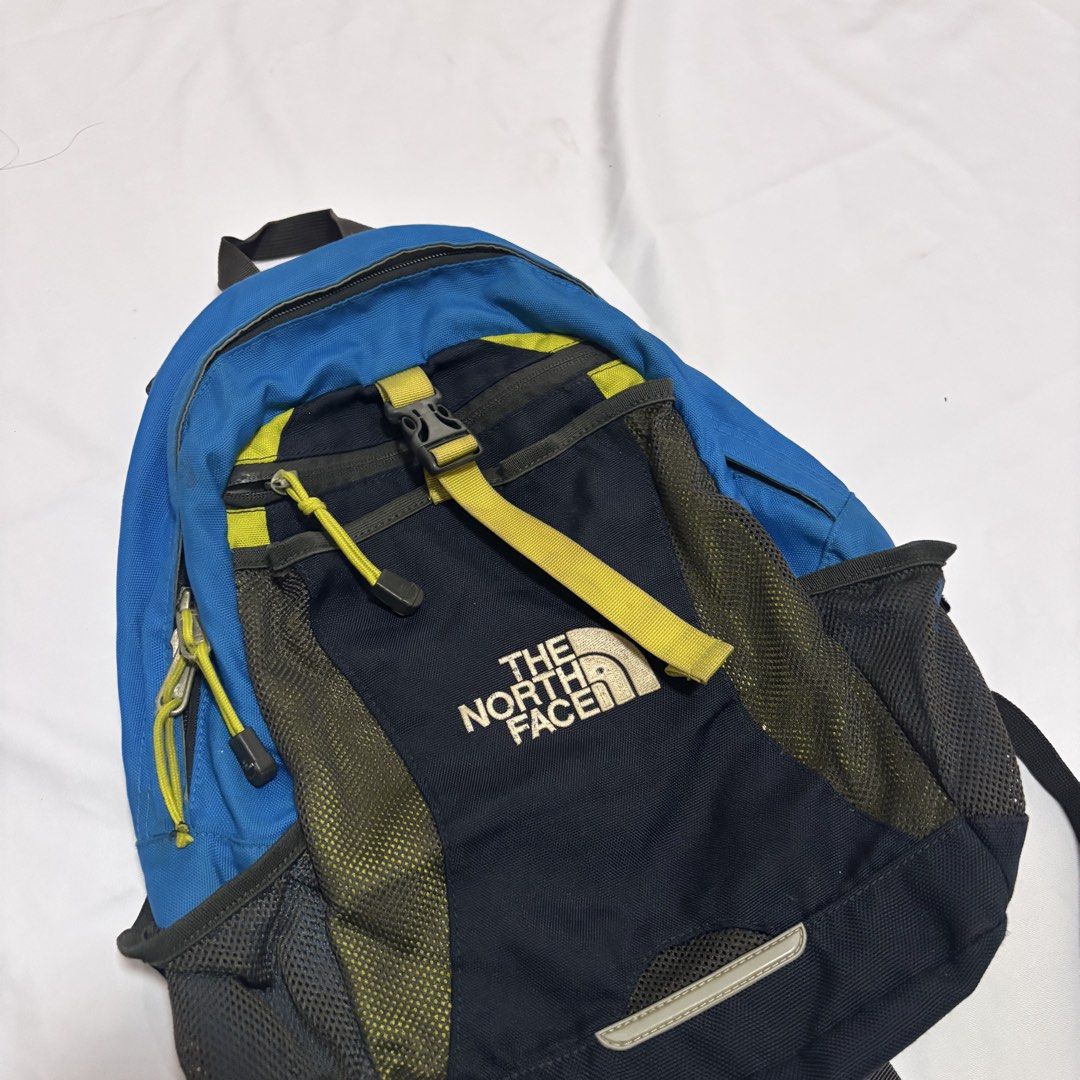 The North Face Small Youth Backpack (Category: Backpacks) located in Imus. Submitted by wear.arca (Listing ID 1468825316, Image 2). Description: - Brand: The North Face - Can fit iPad, water bottle - Flaws: Slight thinning on base fabric, loose garter of side pockets - Body is still good! - Colorway: Blue, Navy, and Yellow - Storage: Main compartment with inner divider, front zipper pocket, and dual mesh side pockets for water bottles - Comfort: 