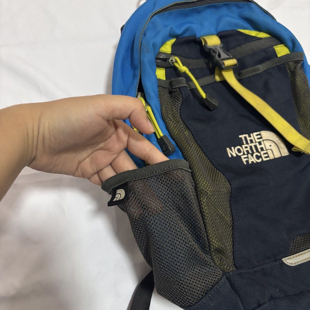 The North Face Small Youth Backpack (Category: Backpacks) located in Imus. Submitted by wear.arca (Listing ID 1468825316, Image 3). Description: - Brand: The North Face - Can fit iPad, water bottle - Flaws: Slight thinning on base fabric, loose garter of side pockets - Body is still good! - Colorway: Blue, Navy, and Yellow - Storage: Main compartment with inner divider, front zipper pocket, and dual mesh side pockets for water bottles - Comfort: 