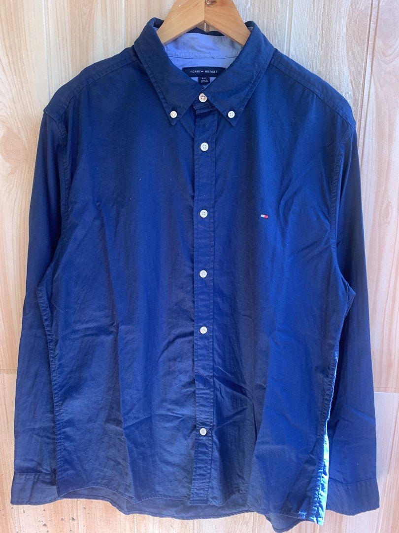 Tommy Hilfiger Blue Button-Down Long Sleeve Size L (Category: Tshirts & Polo Shirts ) located in Barobo. Submitted by pammythrift (Listing ID 1468752763, Image 2). Description: - Brand: Tommy Hilfiger - Color: Dark blue with contrasting light blue inner collar - Size: L (180/108B) - Material: 100% Cotton (Made in Sri Lanka) - Design: Classic button-down collar, front button closure, and embroidered flag logo on left chest - Condition: Clean, well