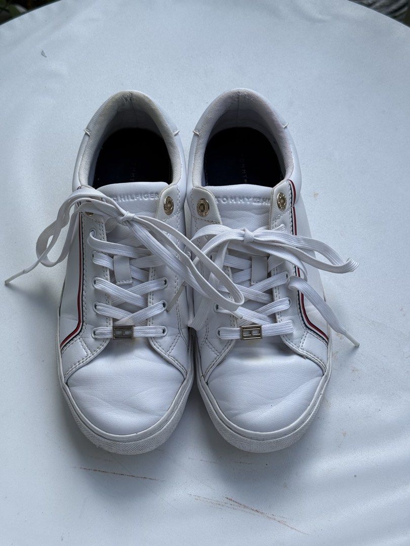 Tommy Hilfiger White Leather Sneakers (Category: Sneakers) located in Taguig. Submitted by shopyumona (Listing ID 1468777495, Image 2). Description: - Brand: Tommy Hilfiger - Material: White leather with fabric lining - Design: Classic low-top with signature red and blue side stripes - Details: Gold-tone eyelets and lace lock hardware - Condition: Pre-owned with wear visible around the collar and outer soles - Perfect for everyday casual wear - B