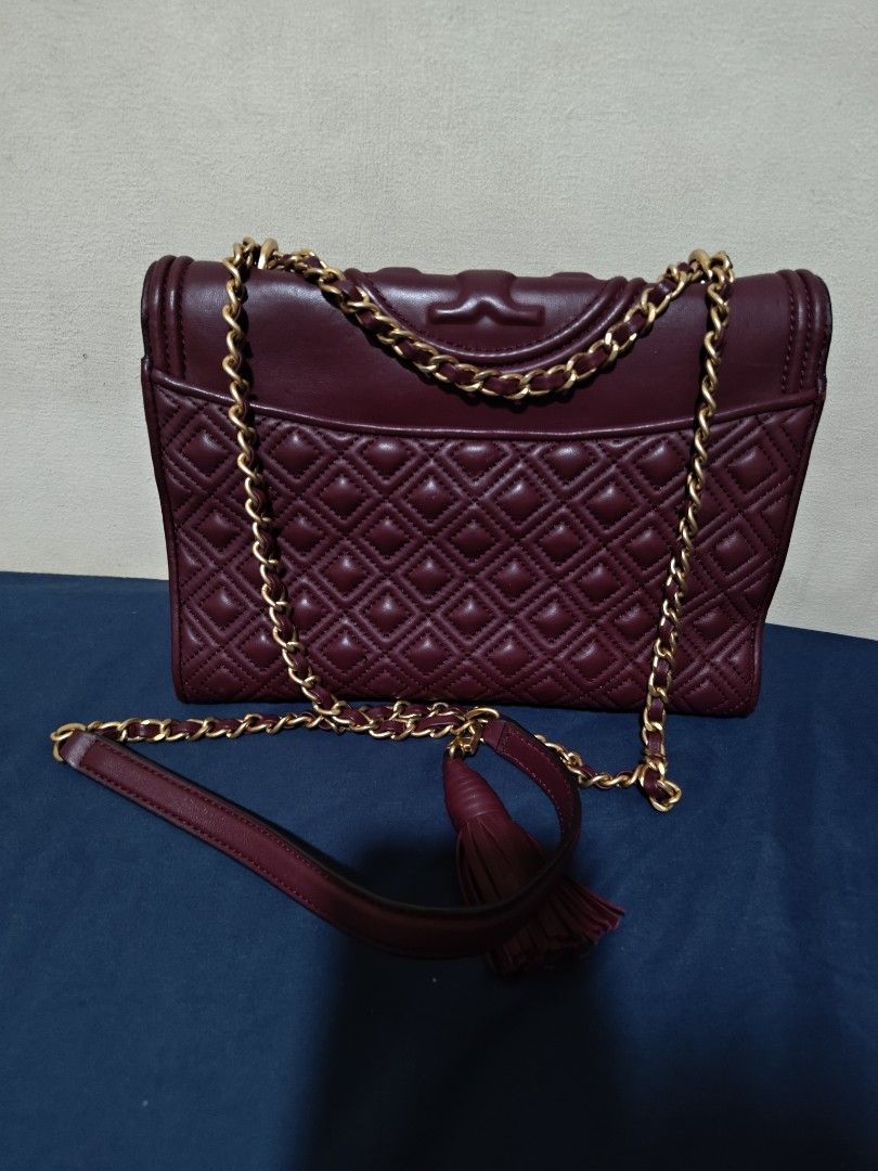 Tory Burch Burgundy Fleming Quilted Leather Shoulder Bag (Category: Luxury Bags & Wallets) located in Valenzuela. Submitted by wisewhale_46982b (Listing ID 1468768983, Image 2). Description: - Brand: Tory Burch - Color: Rich Burgundy - Material: Quilted leather body with smooth leather flap - Hardware: Gold-tone chain strap with leather shoulder guard - Details: Embossed T logo, matching tassel charm, and magnetic flap closure - Interior: Clean l