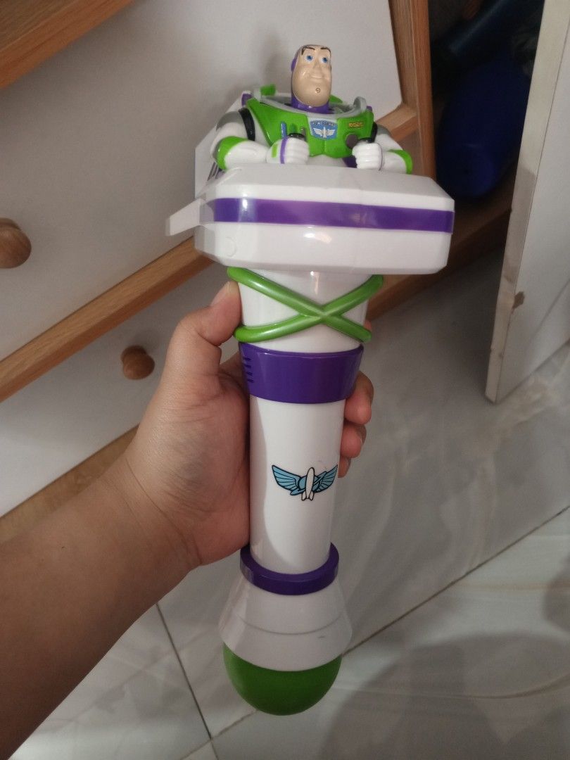Toy Story Buzz Lightyear Bubble Blower Wand (Category: Action & Battle Toys) located in Manila. Submitted by iccythng0216 (Listing ID 1468741917, Image 3). Description: Buzz Lightyear bubble blower toy. White body with purple and green details. Features a bubble wand nozzle on the front with three red and yellow circular ports behind it. Action figure of Buzz Lightyear seated on top of the blaster unit. Handle has a purple power switch on the sid