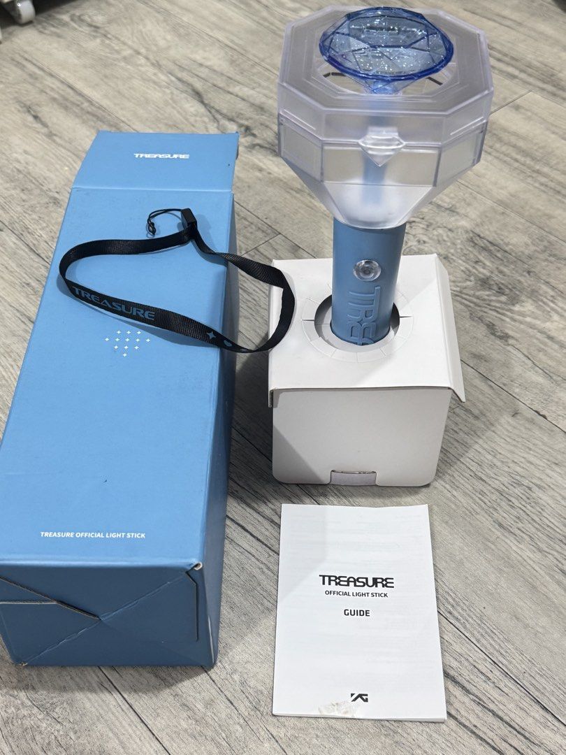 TREASURE Official Light Stick V1 with Box and Strap (Category: Music Accessories) located in Manila. Submitted by carsonn.y (Listing ID 1468827764, Image 3). Description: Official TREASURE light stick in light blue. Includes the original blue outer box, inner stand packaging, black wrist strap with branding, and the instruction guide booklet. I have only used this once during their concert. .