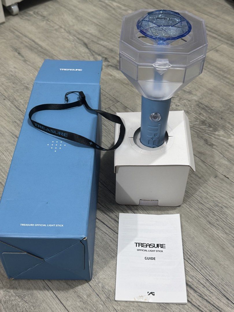 TREASURE Official Light Stick V1 with Box and Strap (Category: Music Accessories) located in Manila. Submitted by carsonn.y (Listing ID 1468827764, Image 1). Description: Official TREASURE light stick in light blue. Includes the original blue outer box, inner stand packaging, black wrist strap with branding, and the instruction guide booklet. I have only used this once during their concert. .
