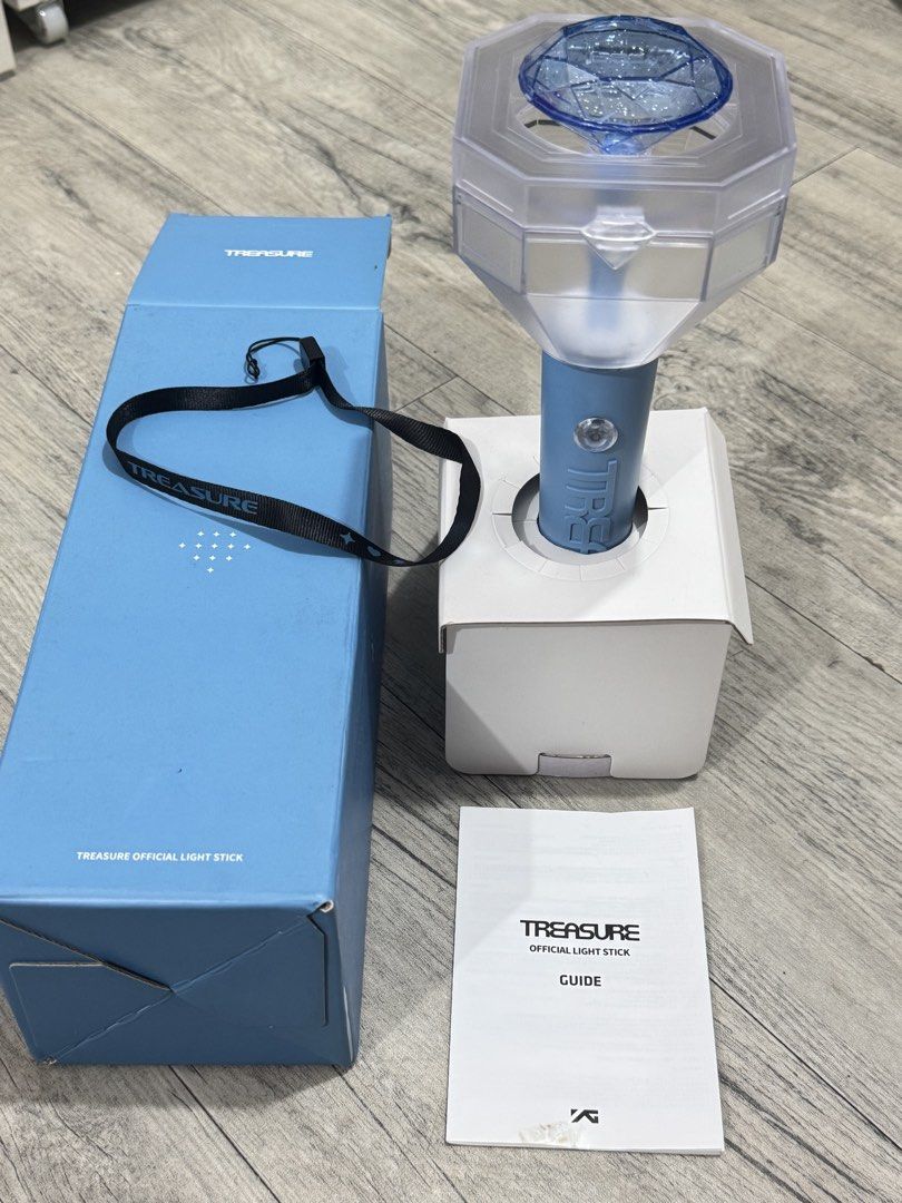 TREASURE Official Light Stick V1 with Box and Strap (Category: Music Accessories) located in Manila. Submitted by carsonn.y (Listing ID 1468827764, Image 2). Description: Official TREASURE light stick in light blue. Includes the original blue outer box, inner stand packaging, black wrist strap with branding, and the instruction guide booklet. I have only used this once during their concert. .