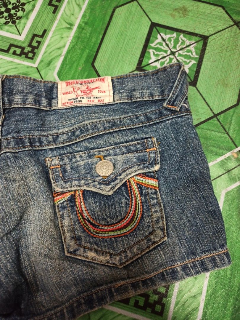 True Religion Rainbow Pocket Denim Shorts (Category: Shorts) located in Tagbilaran City. Submitted by delasierra39181 (Listing ID 1468788179, Image 2). Description: - Brand: True Religion - Wash: Medium blue with subtle fading - Details: Classic Buddha leather patch on back waistband - Pockets: Signature flap pockets with vibrant rainbow stitching - Hardware: Branded metal buttons and zip fly - Fit: Five-pocket styling, comfortable denim cut.