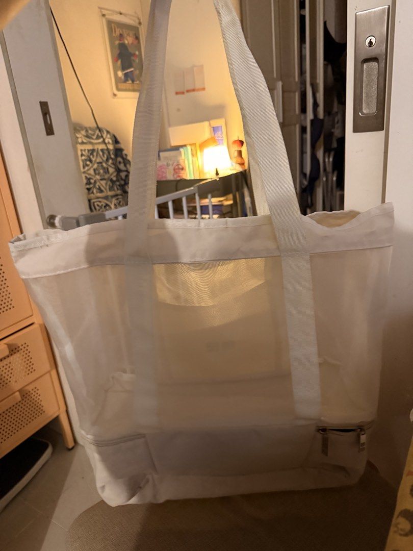 Uniqlo White Mesh Tote Bag With Bottom Compartment (Category: Tote Bags) located in Mandaluyong City. Submitted by ohayouclub (Listing ID 1468854968, Image 2). Description: - Brand: Uniqlo - Color: White - Material: Lightweight and durable mesh - Features: Sturdy top handles for easy carrying - Pocket: Front pocket with Uniqlo logo patch - Compartment: Handy zip compartment at the bottom - Condition: Clean overall.