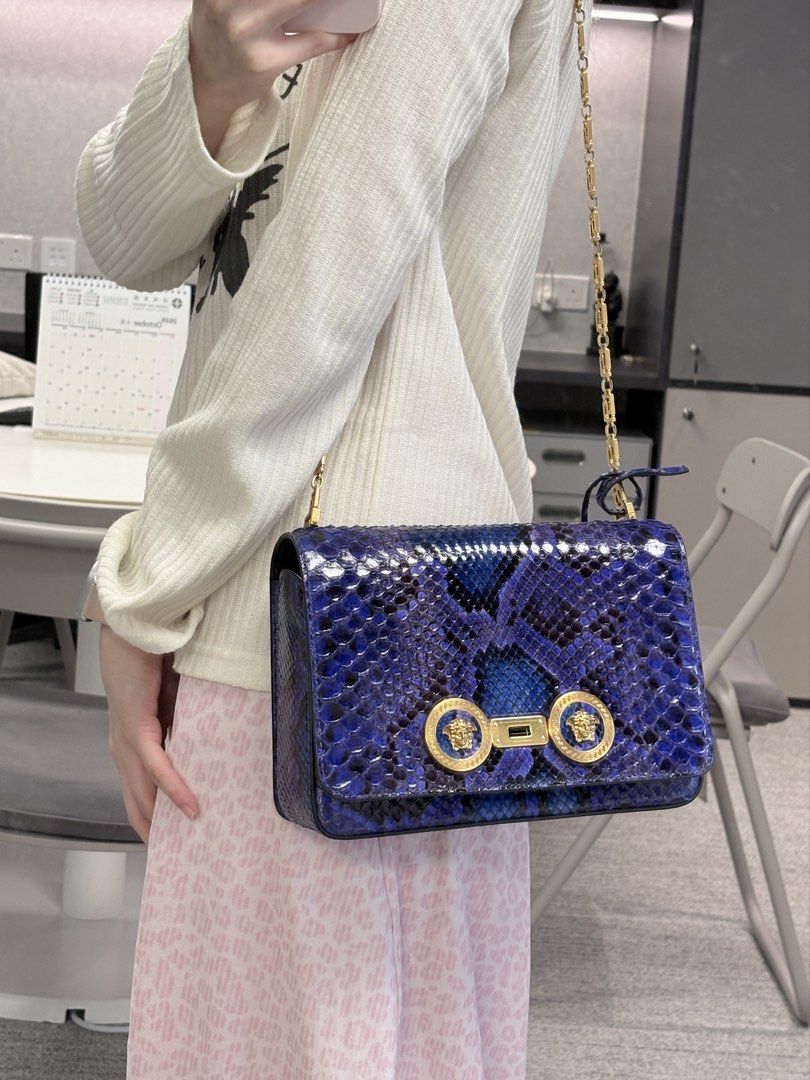 Versace Tribute ( Medium Python Leather) （分類：手袋及銀包）位於 Hong Kong。 由 just.wanna.sell.store 提交（商品編號 1467746909，圖片 2）。簡介： Versace Tribute ( Medium Python Leather) 設計與特色： ✨天然蟒蛇皮打造，保留材質獨特立體質感&豐富鱗片紋理。 ✨精湛工藝染色，呈現神秘奢華的藍紫漸變色調，不同光線下折射出光澤 ✨翻蓋正面飾有圓形金屬扣，中央鑲嵌品牌標誌性的希臘神話「美杜莎頭像」圖案 ✨肩帶採用拼接設計，由質感厚實的金色金屬鏈條構成，並融入了幾何風格的希臘迴紋（Greek Key）圖案 ✨袋身背面設有外置插袋，無需打開翻蓋即可快速收納卡片。 尺寸： 寬：20 - 22 cm 高：13 - 14 cm 深：4 - 5 cm 搭配建議： 精緻的同色系（Monochromatic） 黑色穿搭，與手袋形成對比 奢華小黑裙（適合正式場合及晚間活動） Desig