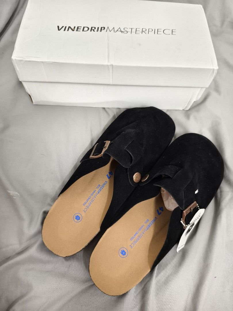 Vinedrip Masterpiece Black Suede Clogs Size 47 (Category: Slippers & Slides) located in Angeles City. Submitted by measaliman02351 (Listing ID 1468744339, Image 2). Description: - Brand: Vinedrip - Model: Masterpiece Clogs - Color: Black - Material: Suede - Size: 47 - Condition: Brand new, never worn, pristine condition - Includes: Original white box and tag attached - Features: Slip-on mule design, adjustable buckle strap, and supportive cork fo