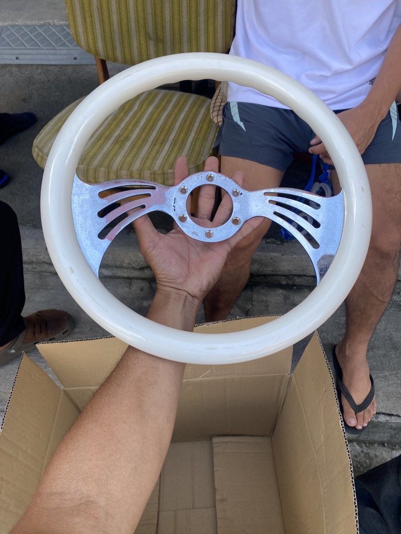 Vintage custom white and chrome steering wheel (Category: Steering, Brakes, Control Parts and Accessories) located in Tagum. Submitted by waaap420 (Listing ID 1468897182, Image 3). Description: - White grip steering wheel with stylish chrome center spokes - Features a sporty slotted spoke design on both sides - Standard multi-bolt pattern for universal compatibility - Shows minor scuffs and wear marks on the white rim and metal surface.