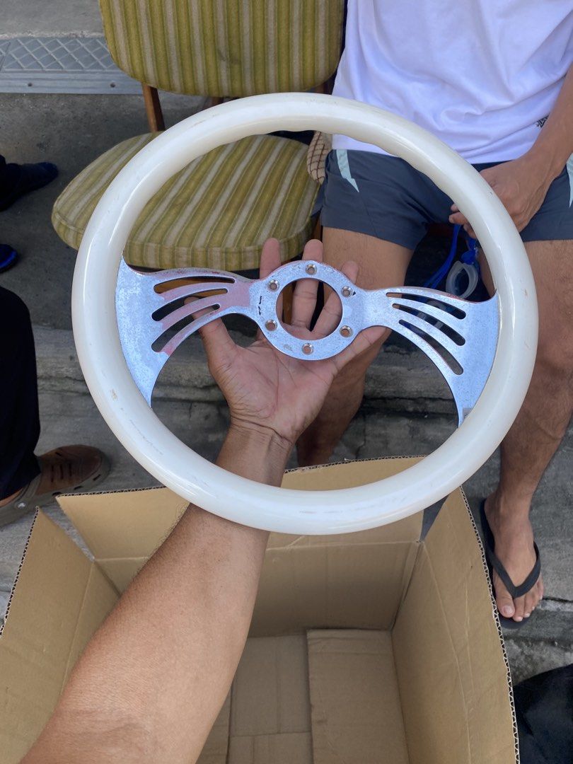 Vintage custom white and chrome steering wheel (Category: Steering, Brakes, Control Parts and Accessories) located in Tagum. Submitted by waaap420 (Listing ID 1468897182, Image 2). Description: - White grip steering wheel with stylish chrome center spokes - Features a sporty slotted spoke design on both sides - Standard multi-bolt pattern for universal compatibility - Shows minor scuffs and wear marks on the white rim and metal surface.