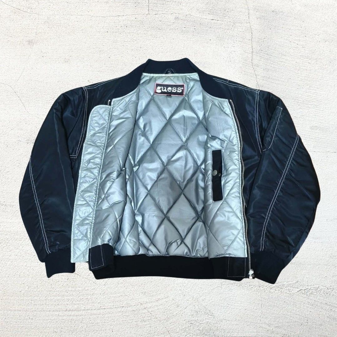 Vintage Guess Black Bomber Jacket with Quilted Lining (Category: Coats, Jackets and Outerwear) located in Baguio. Submitted by hevimetl (Listing ID 1468853529, Image 3). Description: - Brand: Guess - Color: Classic Black with contrasting white stitching - Interior: Quilted silver lining for extra warmth - Pockets: Dual side pockets and sleeve utility pocket - Details: Small chest graphic, bold Guess branding on the back, and ribbed collar, cuffs,