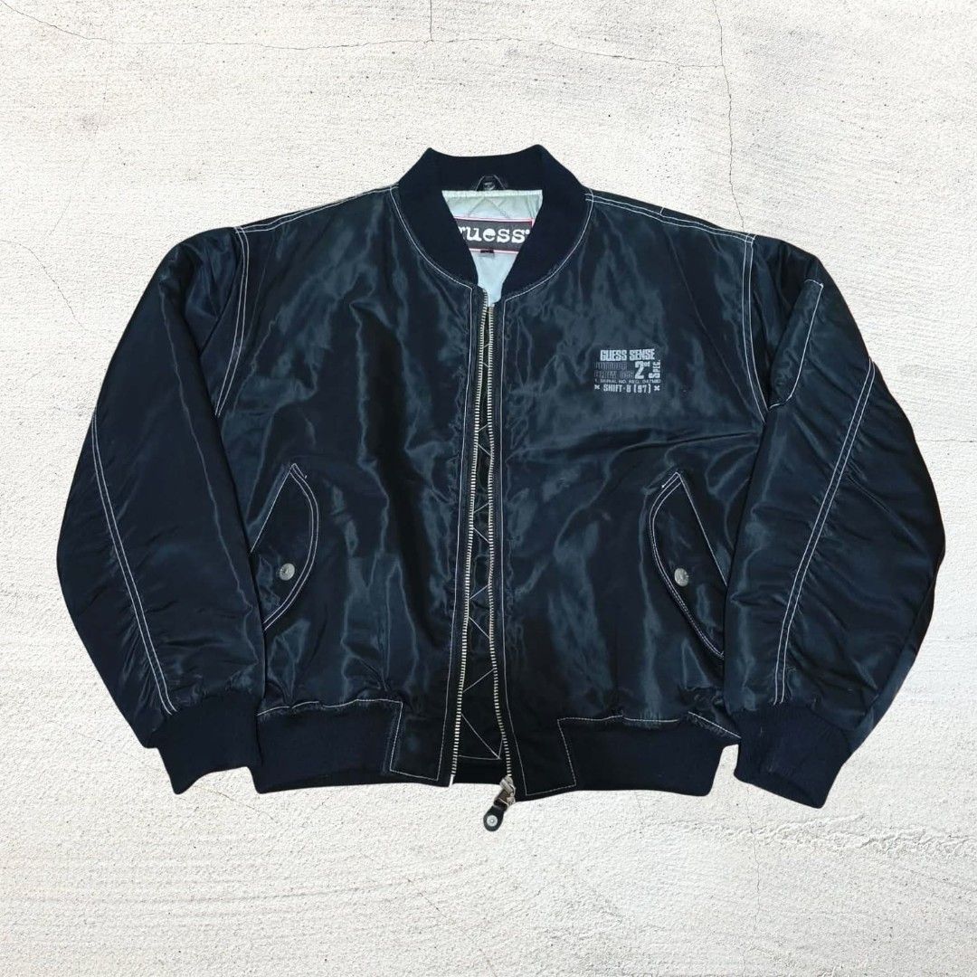 Vintage Guess Black Bomber Jacket with Quilted Lining (Category: Coats, Jackets and Outerwear) located in Baguio. Submitted by hevimetl (Listing ID 1468853529, Image 1). Description: - Brand: Guess - Color: Classic Black with contrasting white stitching - Interior: Quilted silver lining for extra warmth - Pockets: Dual side pockets and sleeve utility pocket - Details: Small chest graphic, bold Guess branding on the back, and ribbed collar, cuffs,