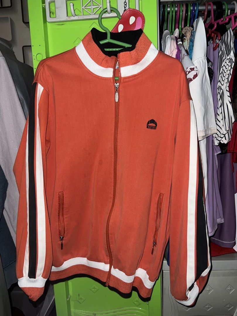Vintage Orange Track Jacket with Striped Sleeves (Category: Coats, Jackets and Outerwear) located in Manila. Submitted by shavonee04 (Listing ID 1468799739, Image 1). Description: - Color: Vibrant orange with black and white sleeve stripes - Closure: Full front zipper with high ribbed collar - Pockets: Dual zippered front pockets for security - Details: Small embroidered logo patch on the left chest - Fit: Comfortable fit with ribbed cuffs and he