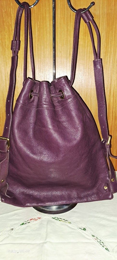 Vivienne Westwood drawstring leather bucket backpack orb logo (Category: Backpacks) located in Baguio. Submitted by mng_assorted_baguio (Listing ID 1468836224, Image 2). Description: - Brand: Vivienne Westwood - Color: Deep Purple - Material: Supple pebbled leather with contrasting dark stitching - Hardware: Antiqued gold-tone - Closure: Drawstring with adjustable shoulder straps - Features: Distinctive metallic orb logo on the front and roomy in
