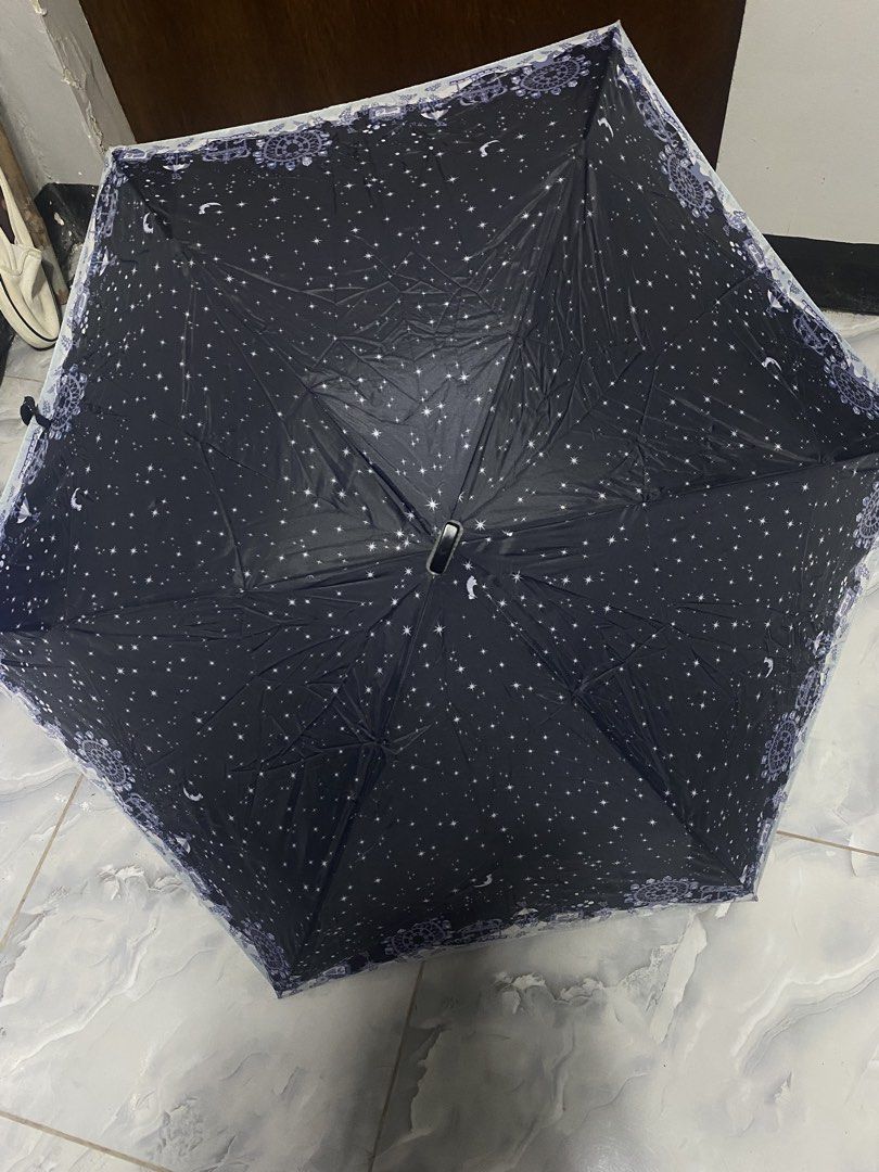 Waterfront Foldable Umbrella Navy Blue Starry Night Pattern (Category: Umbrellas) located in Pasacao. Submitted by wengpullar37205 (Listing ID 1468786297, Image 2). Description: - Brand/Model: Waterfront compact folding umbrella - Design: Navy blue canopy with cute white stars, moons, and decorative border - Portability: Handy size, easy to toss into a tote bag or backpack - Features: Manual open/close mechanism, flat black handle with attached w