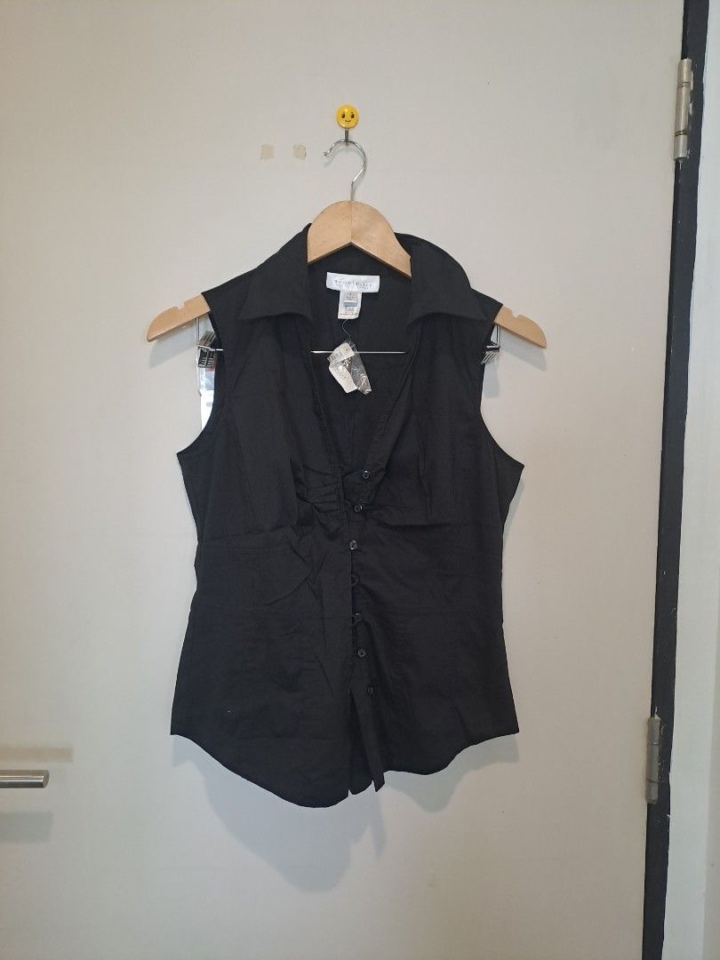 WHBM SLEEVELESS NEW (Category: Undergarments & Loungewear) located in Manila. Submitted by joanbalde39643 (Listing ID 1468754106, Image 1). Description: The item shown is a black sleeveless collared button-down blouse featuring distinct pleated/ruched vertical detailing down the center placket. It has a structured spread collar, a contoured princess-cut silhouette, and curved hem detailing..
