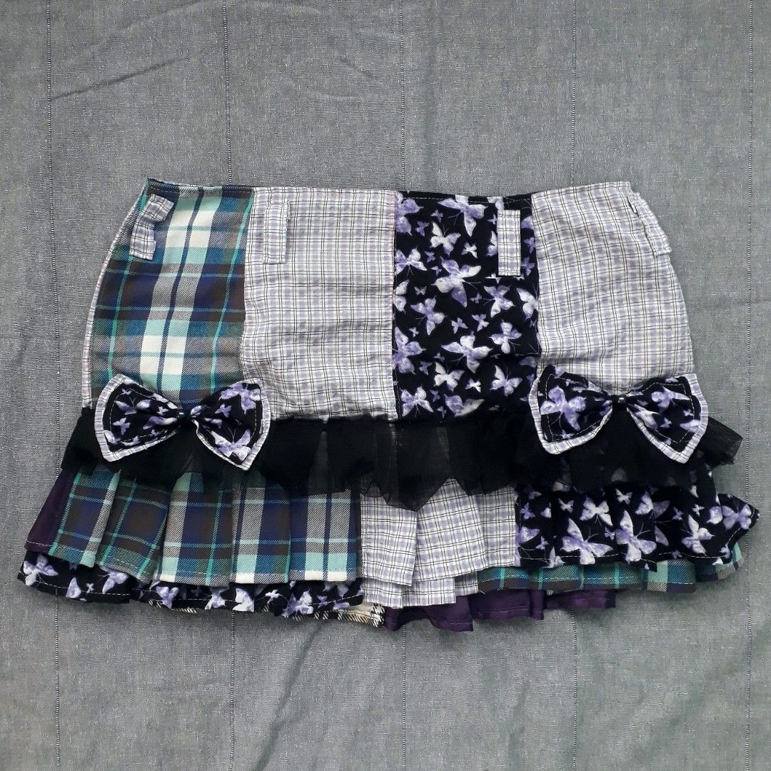 Whimsigoth Patchwork Pleated Mini Skirt (Category: Skirts) located in Cabanatuan. Submitted by madeby_csnstudio (Listing ID 1468729281, Image 2). Description: MEASUREMENTS: Waist: 30 inches (76.2 cm) Hips: 37 inches (93.98 cm) Length: 13 inches (33.02 cm) DETAILS: Constructed from a mix of multi-fabric patchwork panels, the skirt features a contrasting combination of cool-toned blue and grey plaid alongside purple butterfly print sections. Adding