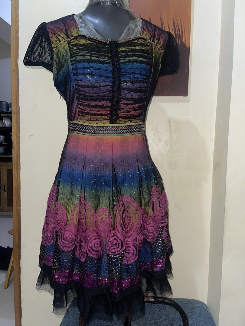 Whimsy Rainbow Mesh Sequin Dress with Rose Applique (Category: Dresses) located in La Trinidad. Submitted by potatothriftlip (Listing ID 1468828031, Image 1). Description: - Vibrant multi-color rainbow gradient mesh dress - Elegant black lace cap sleeves and pleated flared skirt - Lower skirt features striking pink rose appliques and scattered gold sequins - Detailed patterned waistband with a ruffled button placket down the front - Convenient si