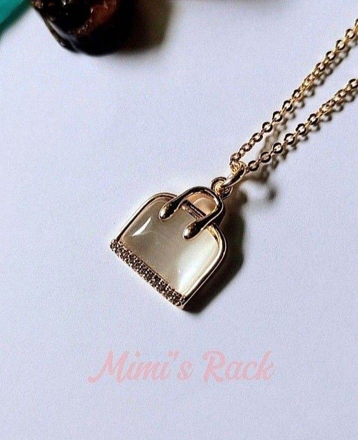 WHITE CAT'S EYE BAG NECKLACE (Category: Necklaces) located in Taguig. Submitted by mimisrack (Listing ID 1468922647, Image 3). Description: 🤍Cute... but lucky. Charm and protection -Bag symbol for wealth and savings -Gold setting for classy glow -Perfect for everyday glam with a touch of prosperity luck -Sweet look. Strong meaning. 🧿 needle chain: approx. 44cm (17in) 🧿 pendant size: 13mm ▪️keep jewelries separated to avoid scratching. ▪️the je