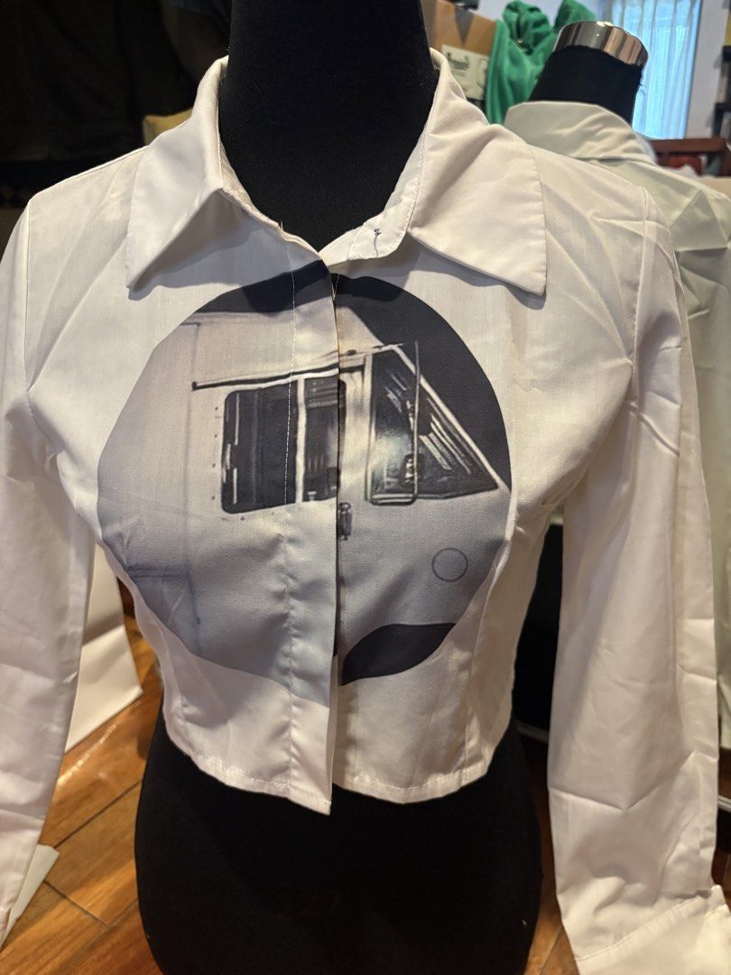 White Crop Top Button-Up Shirt With Graphic Print (Category: Shirts) located in Makati City. Submitted by audrey.hepburn (Listing ID 1468791837, Image 2). Description: - Style: Long-sleeve crop top button-up shirt - Design: Bold black and white vehicle graphic print across the chest - Details: Collared neckline, button-front closure, clean hem - Material: Crisp, structured cotton - Condition: Brand new / Excellent quality - Perfect for: Casual st